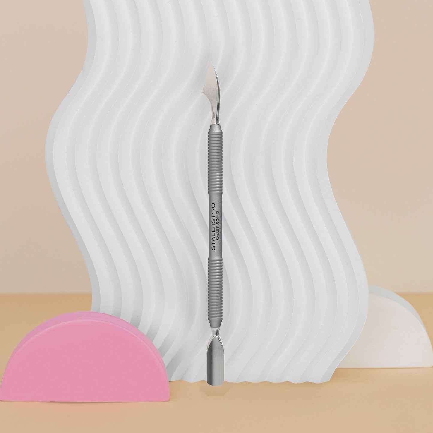 Manicure Pusher SMART 50 TYPE 2 (Rounded Narrow Pusher And Cleaner) with a pink half-circle object on a beige background