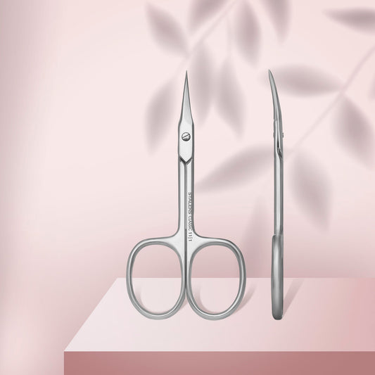 Pair of silver scissors and tweezers on a pink fabric background