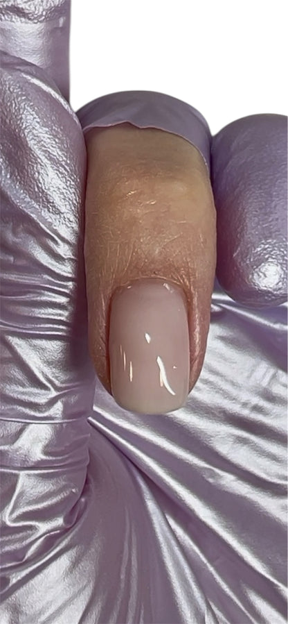 Close-up of a beige nail with a white base coat on a textured white background