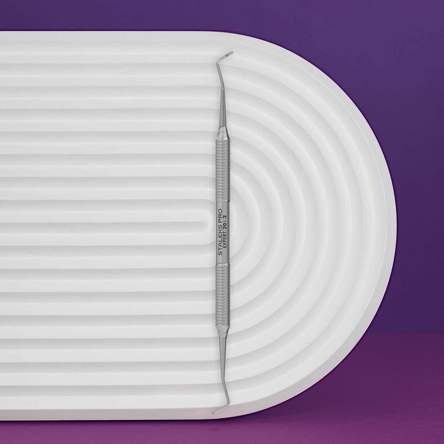 TOENAIL tool on a white tray with a purple background